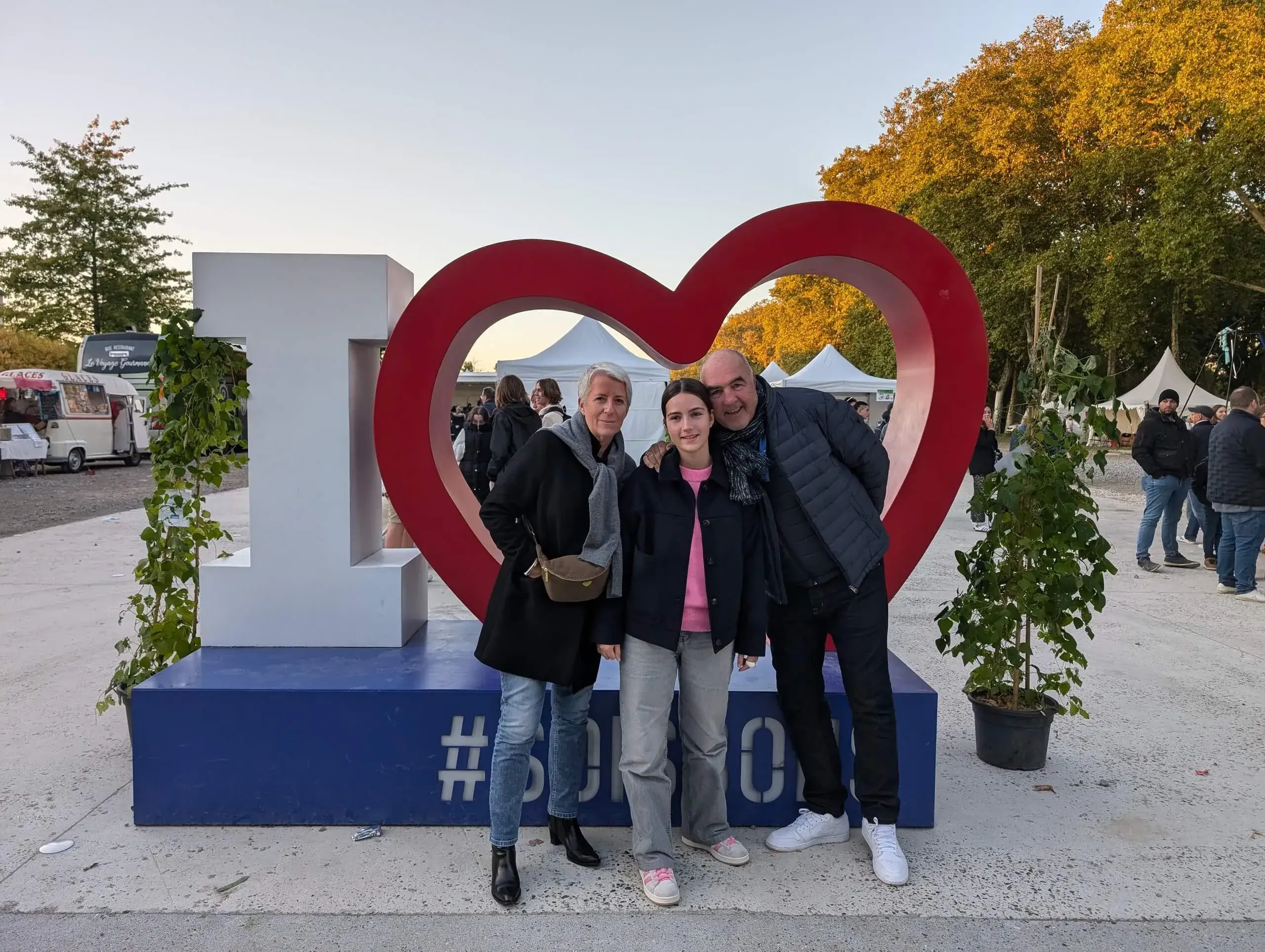 Groupe devant sculpture cœur géant à l'extérieur.