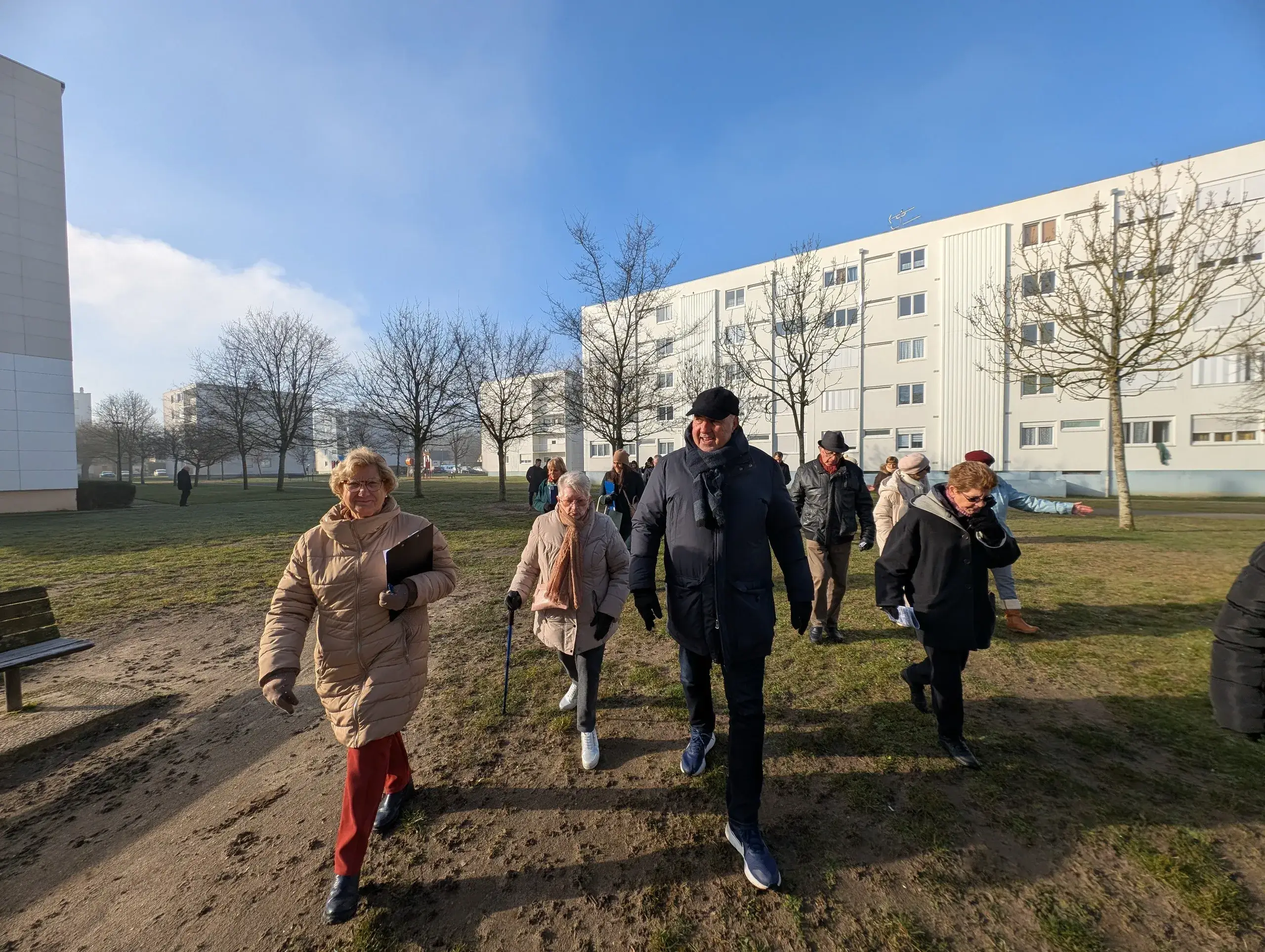 Groupe de personnes marchant dehors par temps ensoleillé.