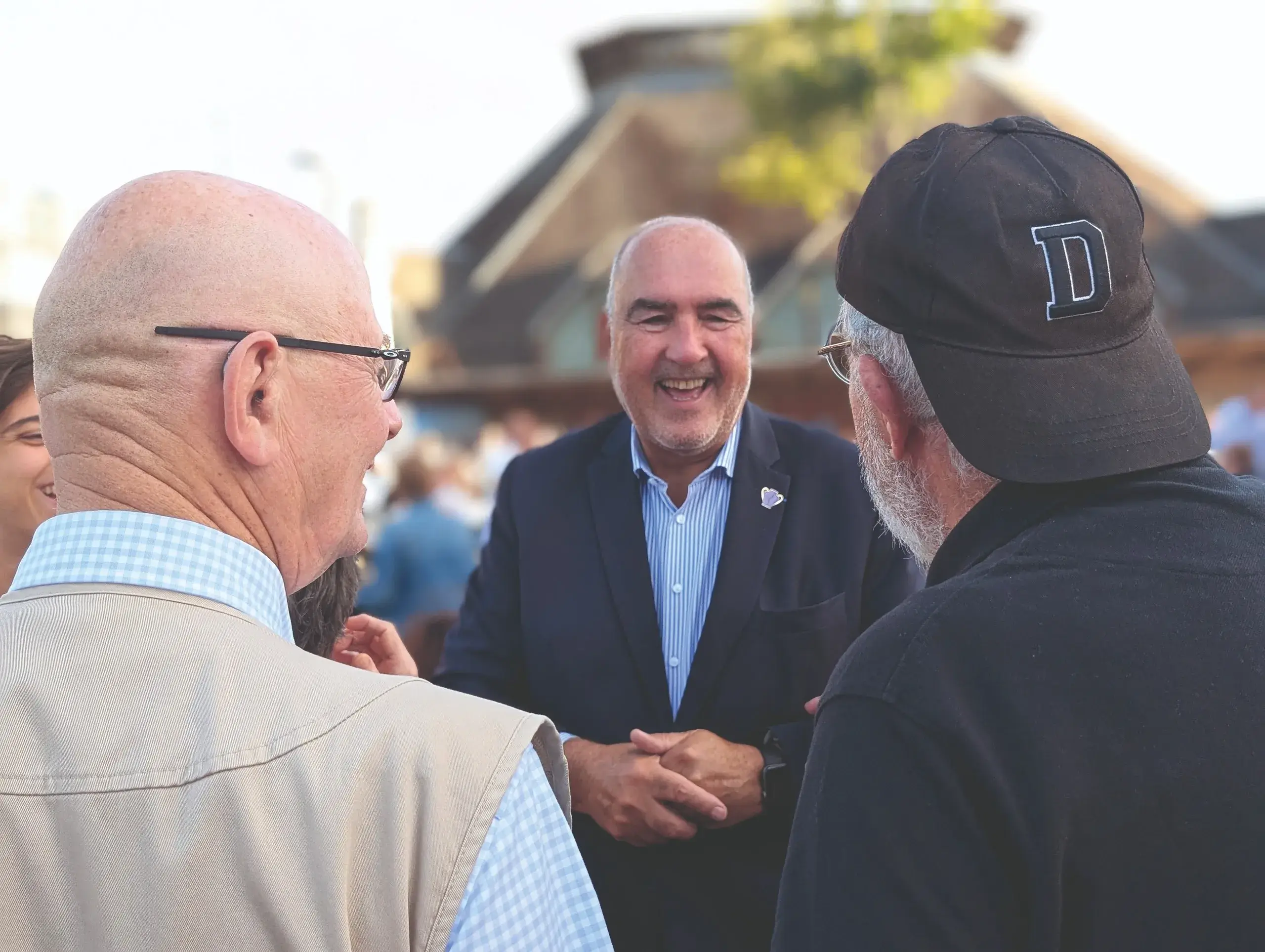 Homme souriant discutant avec deux autres personnes.