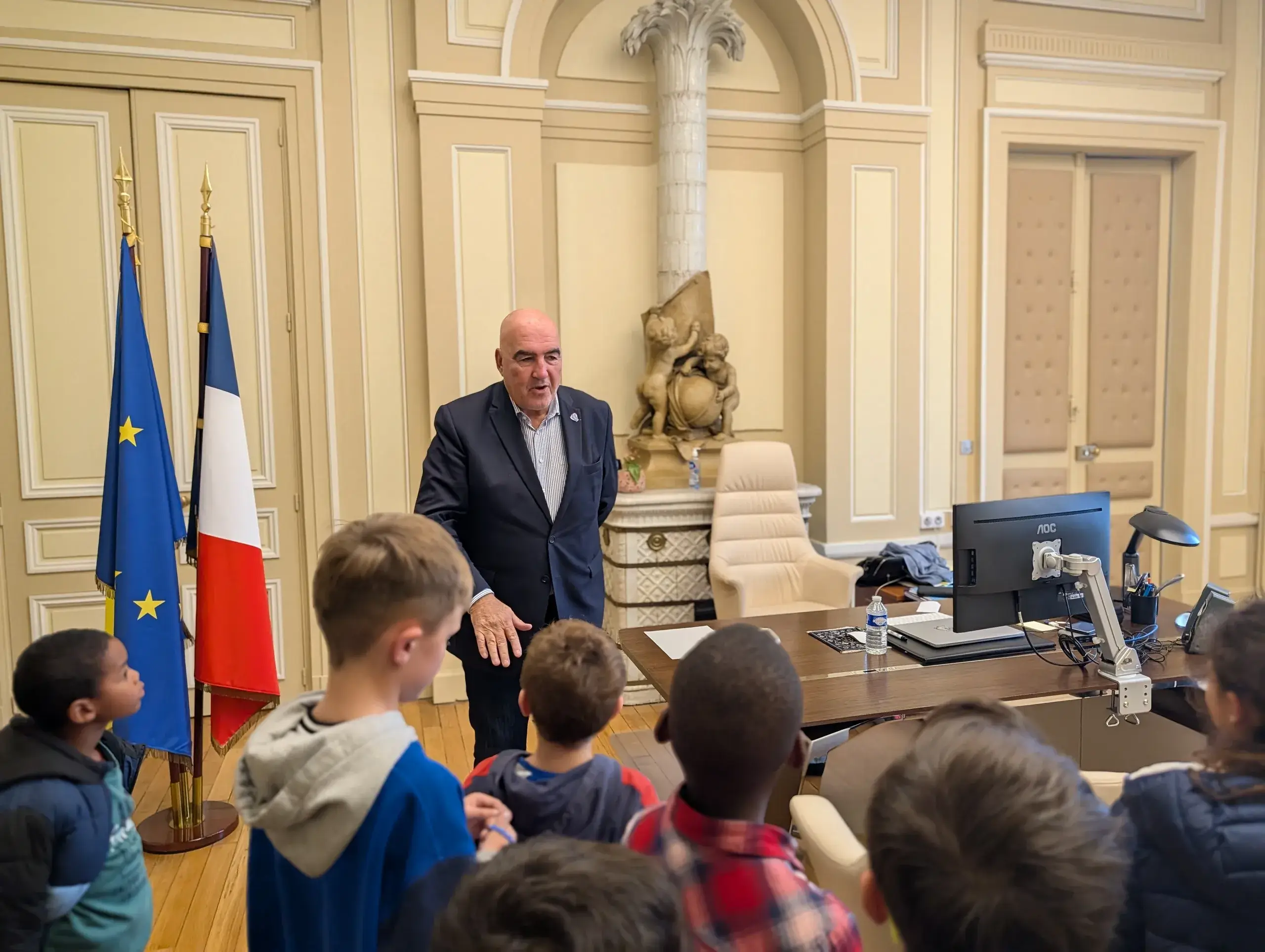 Homme debout devant enfants dans un bureau officiel.