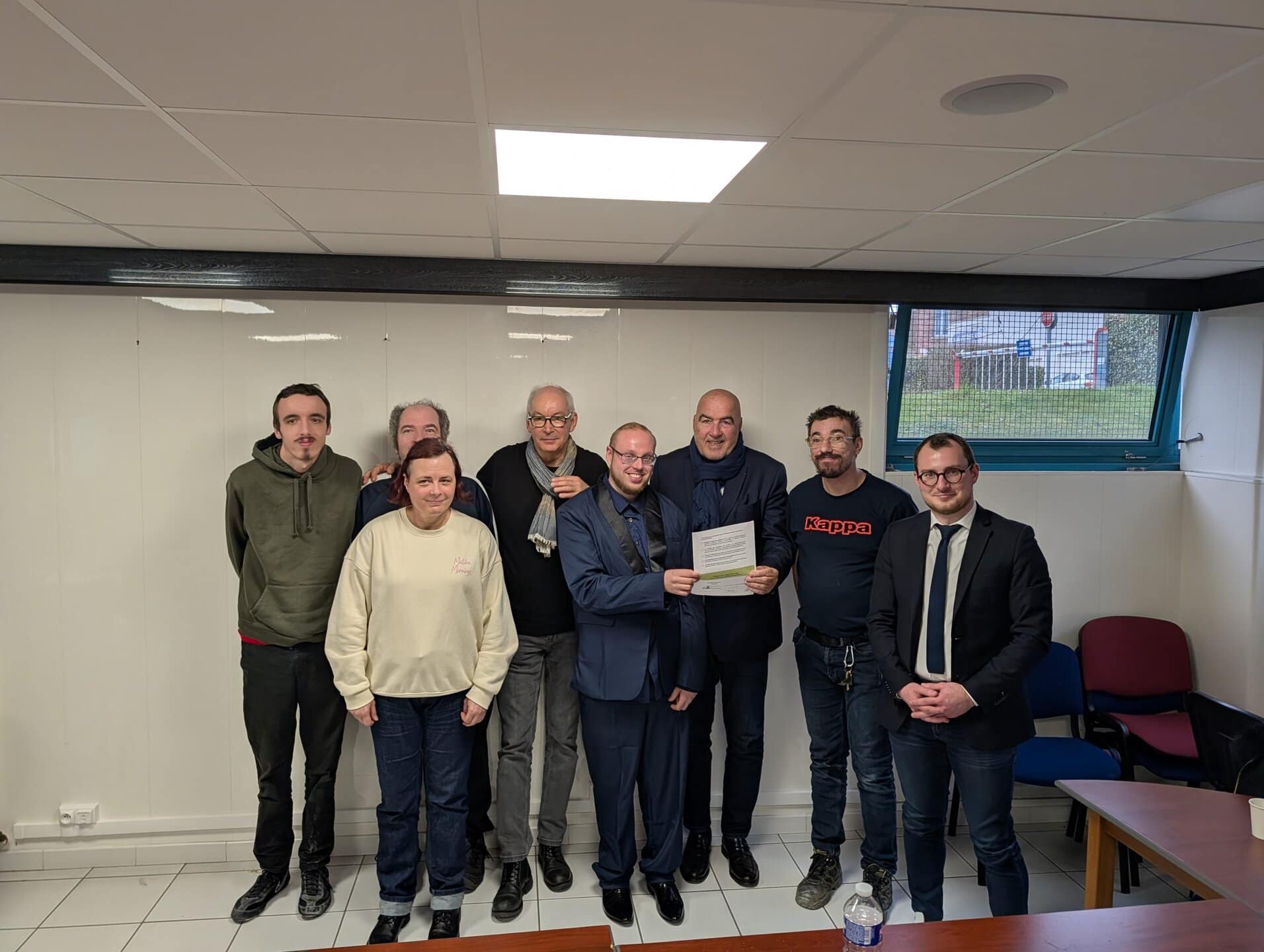 Groupe de personnes posant avec un document.